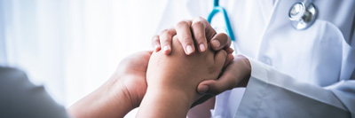 A close up of a doctor holding the hands of a patient